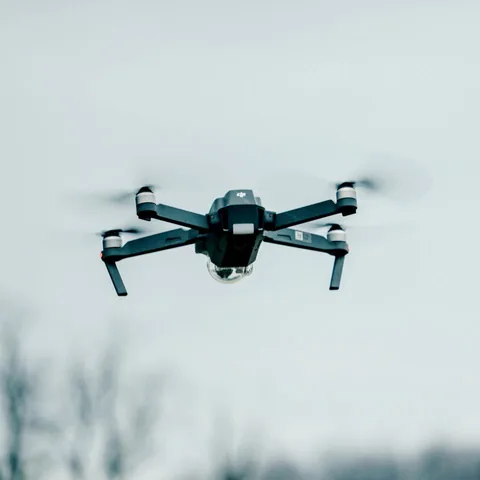 Quadcopter drone in flight against a pale sky